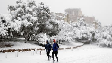 Two men jog as the Parthenon temple is seen atop the Acropolis hill archaeological site during a heavy snowfall in Athens, Greece, on February 16, 2021. (Reuters)