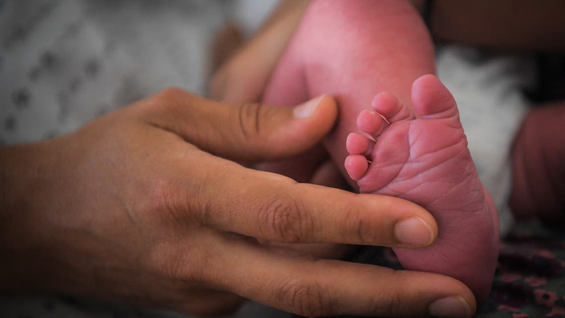 A mother holds the foot of her newborn baby. (AFP)