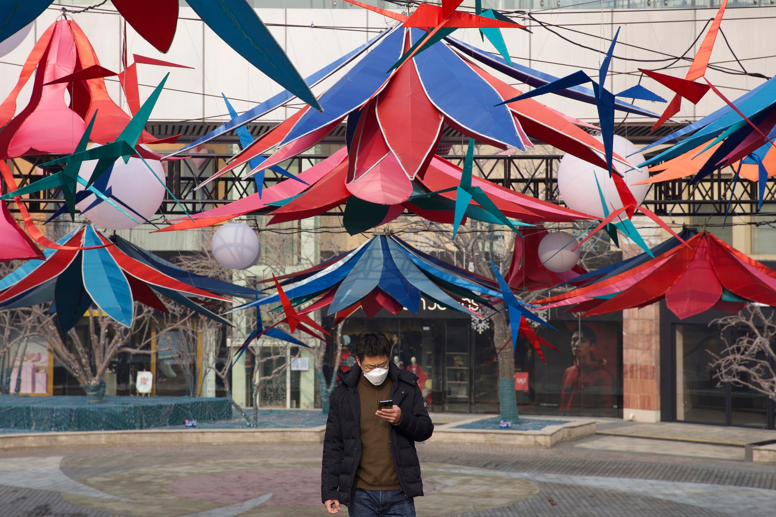 A man uses his phone as he walks through an empty mall district in Beijing, China Wednesday, Feb. 12, 2020. (AP)