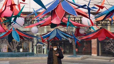 A man uses his phone as he walks through an empty mall district in Beijing, China Wednesday, Feb. 12, 2020. (AP)