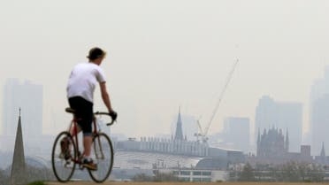 A cyclist rides his bike at the top of Primrose Hill in London on April 3, 2014, as the city below lies shrouded in pollution. A combination of local emissions, light winds and pollution from continental Europe, compounded with dust blown from the Sahara, has prompted health warnings about poor air quality across southern and central England. (AFP)