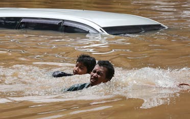  People swim through a flooded neighborhood following heavy rains in Jakarta, Indonesia, Saturday, February 20, 2021. (AP)