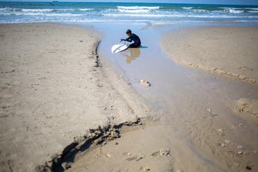 A surfer cleans his tar covered surfboard from an oil spill in the Mediterranean Sea in Gador nature reserve near Hadera, Israel, Saturday, Feb. 20, 2021. (File photo: AP)