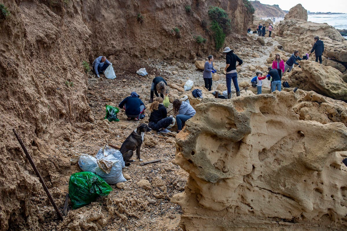 People clean tar from an oil spill in the Mediterranean sea in Gador nature reserve near Hadera, Israel, Saturday, Feb. 20, 2021. (AP/Ariel Schalit)