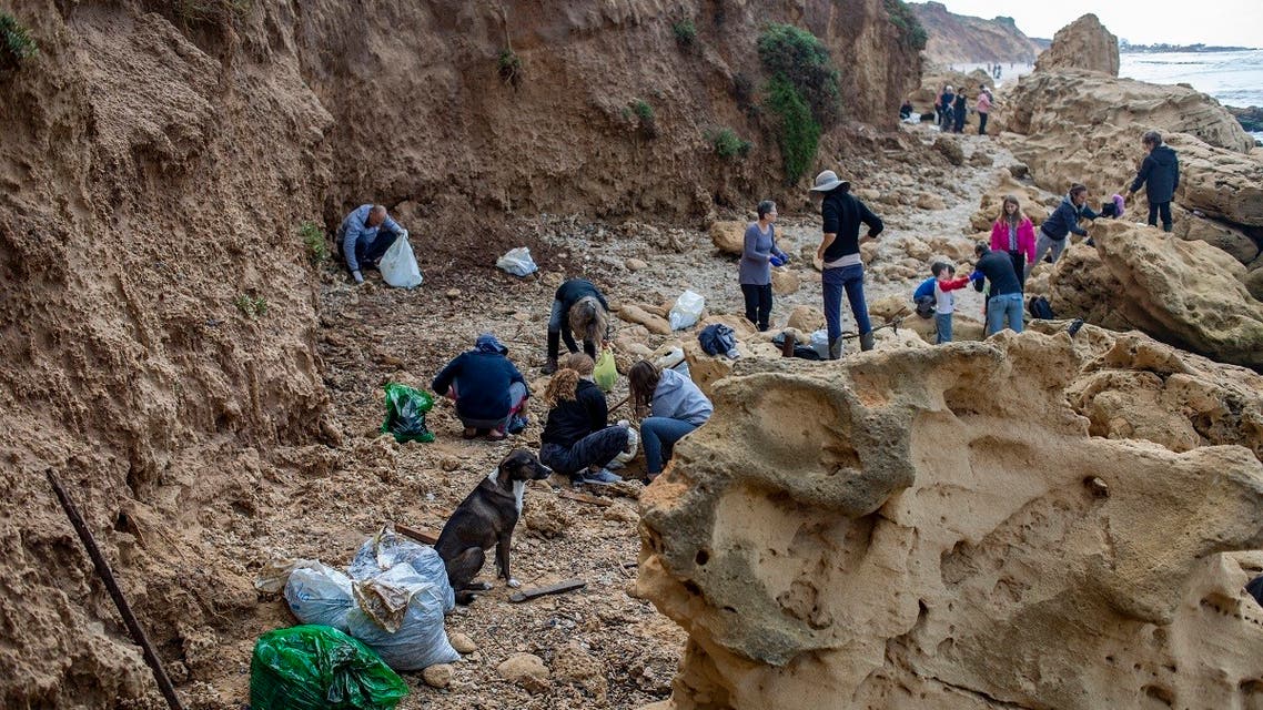 People clean tar from an oil spill in the Mediterranean sea in Gador nature reserve near Hadera, Israel, Saturday, Feb. 20, 2021. (AP/Ariel Schalit)
