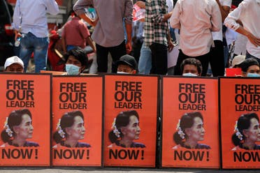 Anti-coup protesters sit behind posters with an image of deposed Myanmar leader Aung San Suu Kyi during a rally in Yangon, Myanmar, Monday, Feb. 22, 2021. (AP)