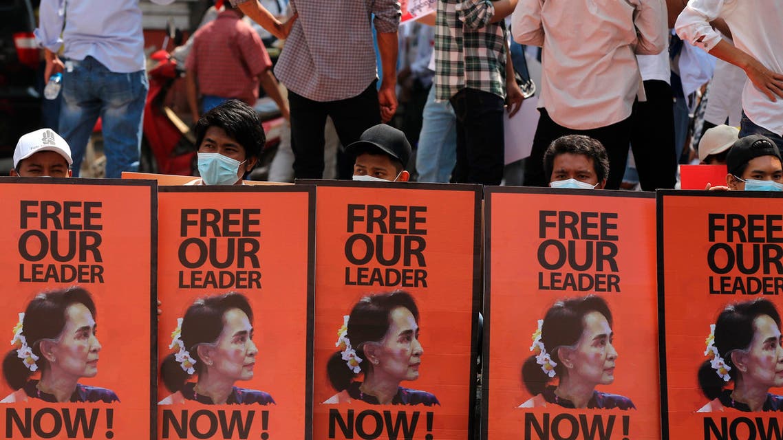 Anti-coup protesters sit behind posters with an image of deposed Myanmar leader Aung San Suu Kyi during a rally in Yangon, Myanmar, Monday, Feb. 22, 2021. (AP)