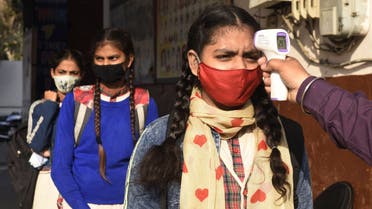 A school worker checks the body temperature of student as they arrive at a government girls school amid the ongoing COVID-19 coronavirus disease pandemic, in Amritsar on February 24, 2021. (File photo: AFP)