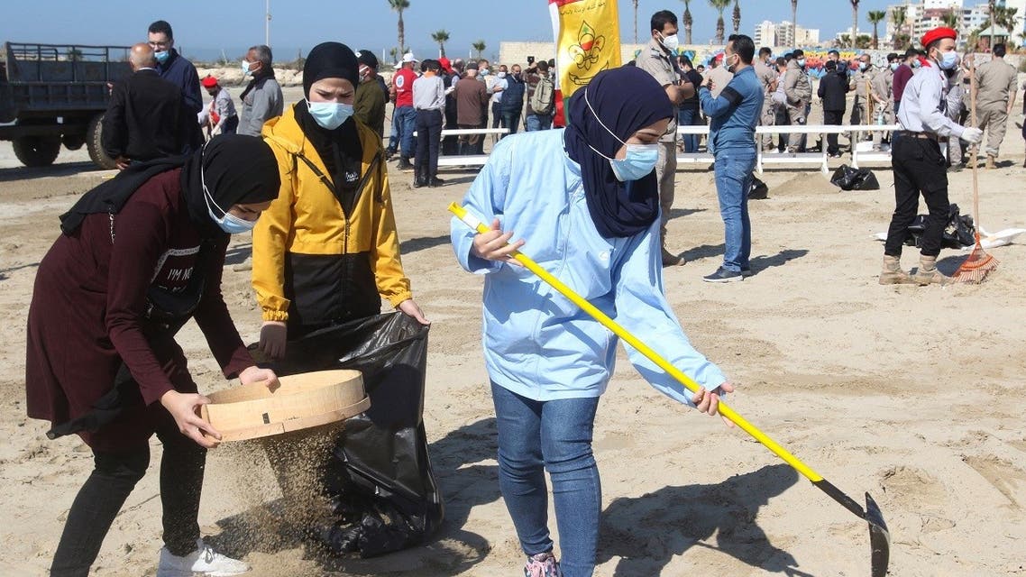 Young volunteers clean a contaminated beach in the southern Lebanese city of Tyre on February 27, 2021. (Mahmoud Zayyat/AFP)