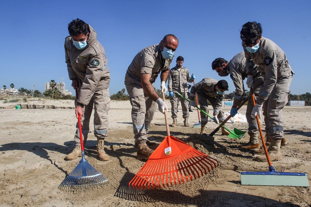 Volunteers from youth associations clean a contaminated beach in the southern Lebanese city of Tyre on February 27, 2021. (Mahmoud Zayyat/AFP)