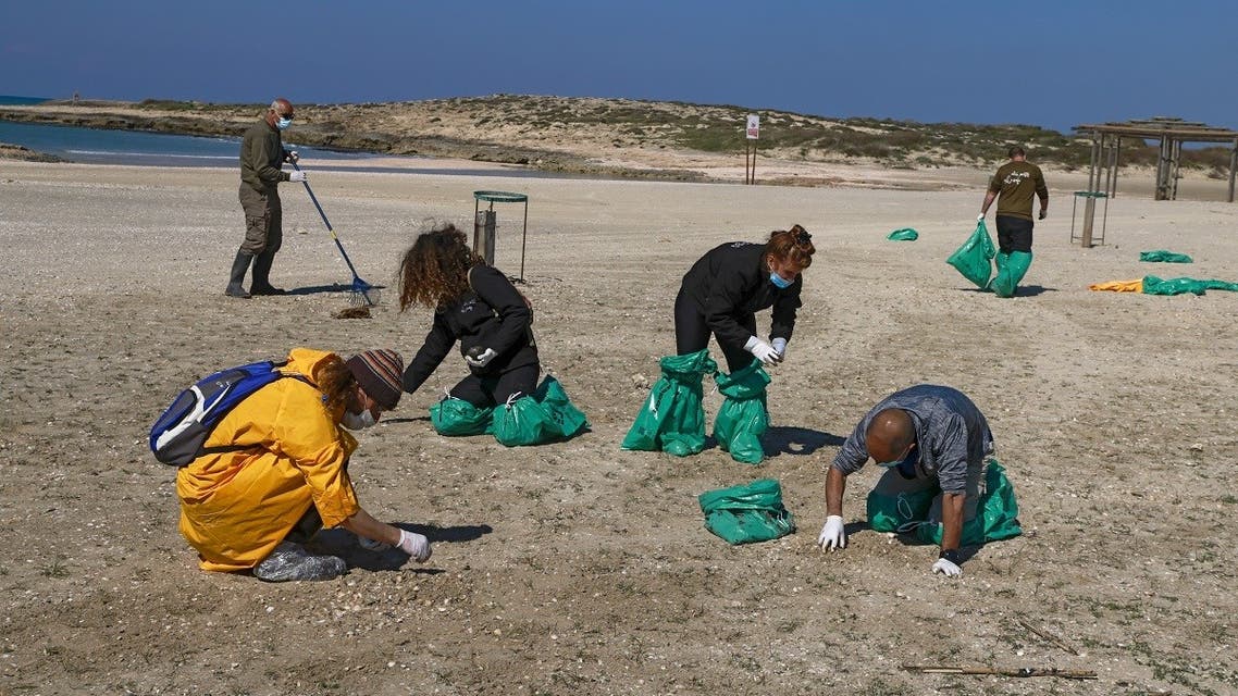 Israel volunteers clean the contaminated HaBonim beach, south the port city of Haifa, on February 21, 2021. (Menahem Kahana/AFP)