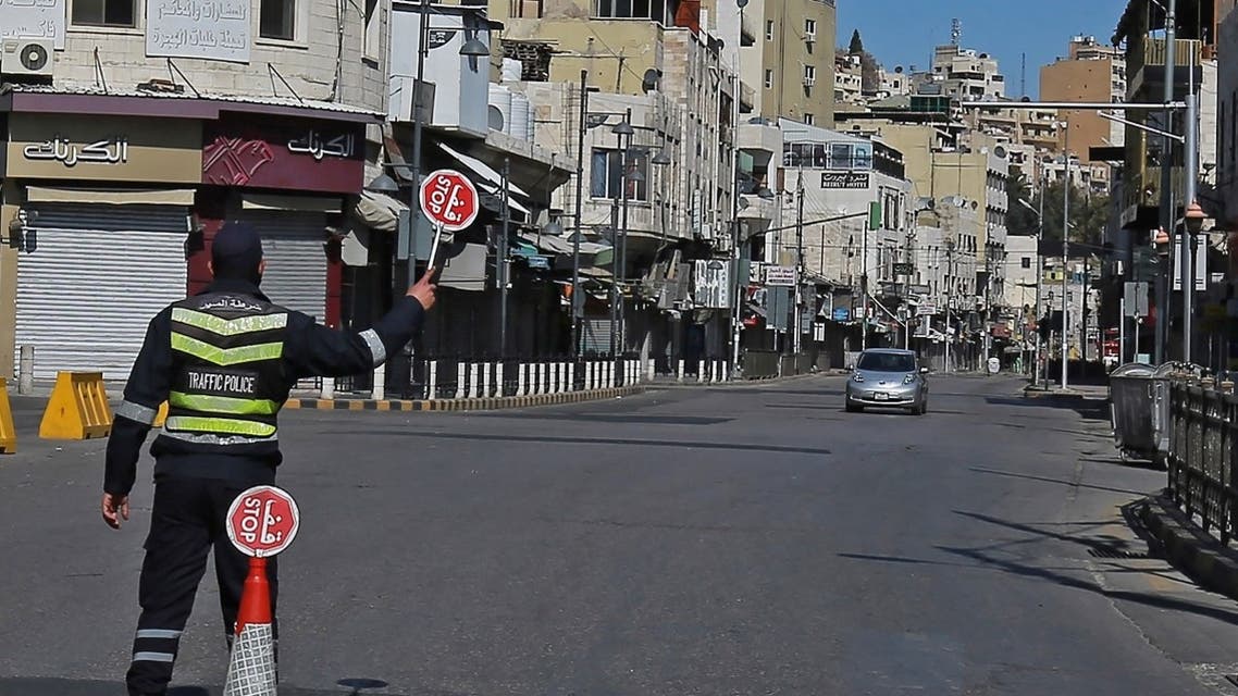 A policeman holds a stop sign in an almost deserted avenue in the Jordanian capital Amman, during a lockdown due to coronavirus pandemic, on February 26, 2021. (Khalil Mazraawi/AFP)