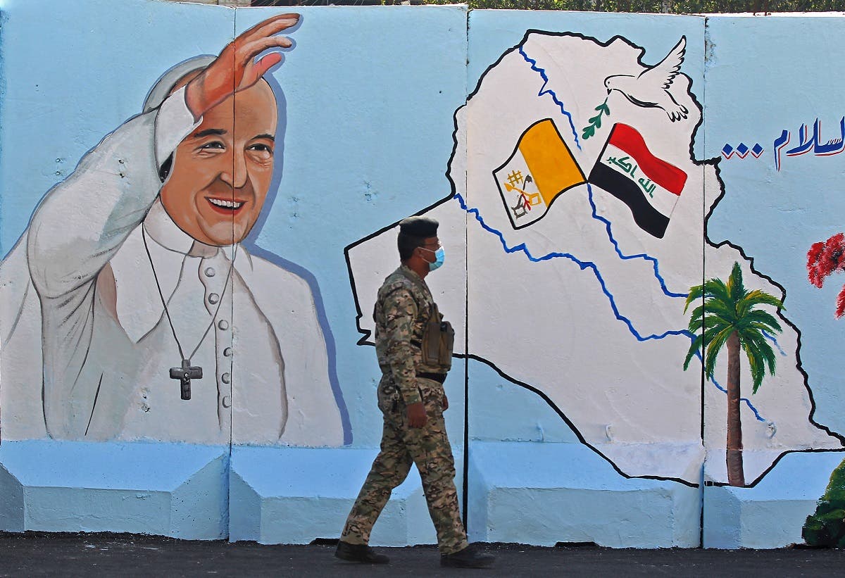 An Iraqi policeman walks by a mural depicting Pope Francis on the outer walls of Our Lady of Salvation (Sayidat al-Najat) Church, in Baghdad on February 22, 2021. (Ahmad al-Rubaye/AFP)
