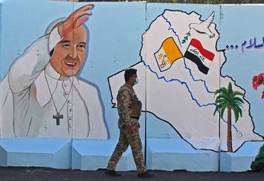 An Iraqi policeman walks by a mural depicting Pope Francis on the outer walls of Our Lady of Salvation (Sayidat al-Najat) Church, in Baghdad on February 22, 2021. (Ahmad al-Rubaye/AFP)