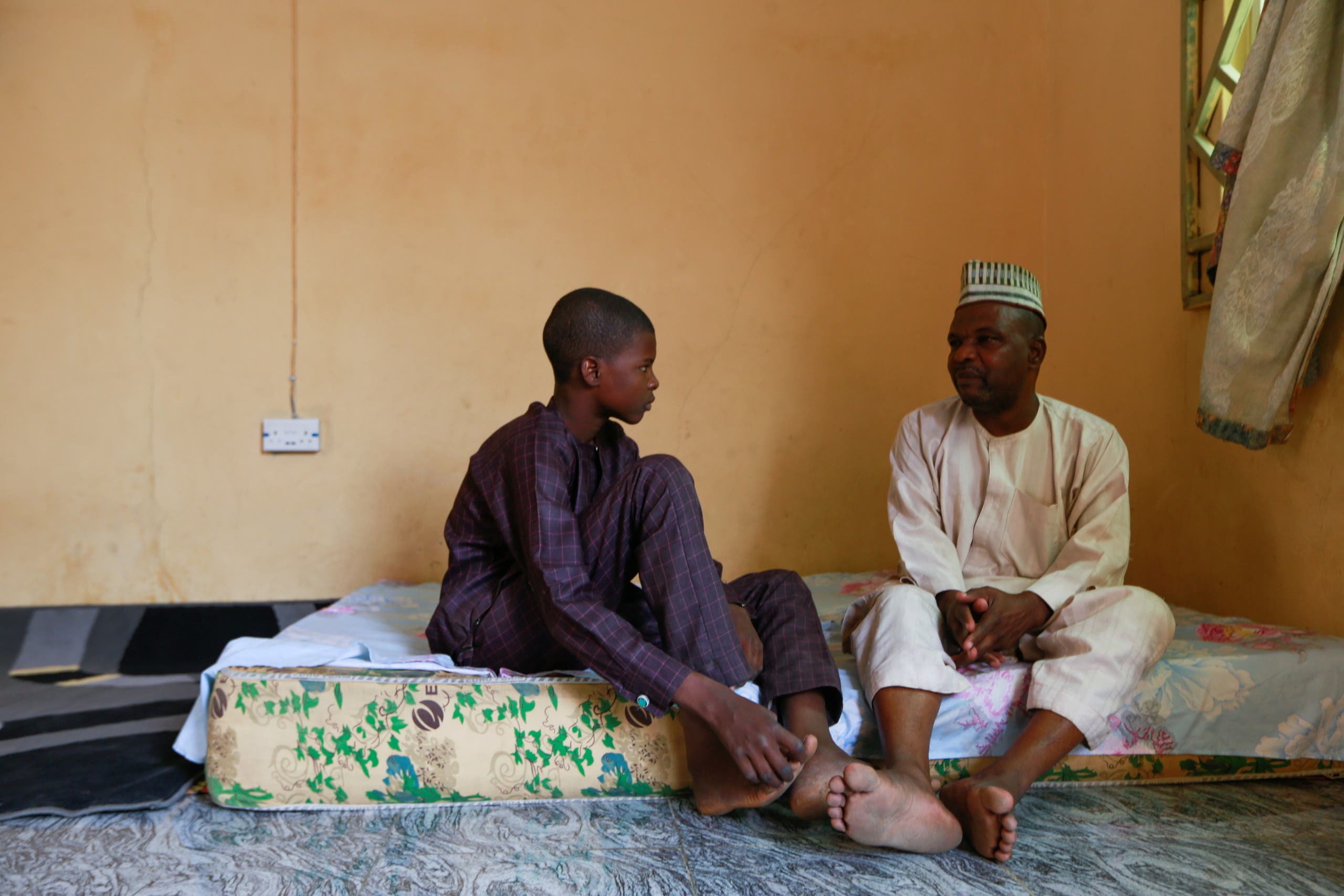 Balarabe Kagara speaks with one of his sons as the family awaits news of the release of two of his daughters after bandits kidnapped them from the JSS Jangebe school, in Zamfara, Nigeria February 28, 2021. (Reuters)