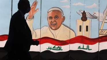 An Iraqi man walks by a mural depicting Pope Francis on the outer walls of Our Lady of Salvation (Sayidat al-Najat) Church, in Baghdad on February 22, 2021. (AFP)