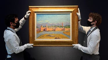 Art handlers pose with 'Tower of the Katoubia Mosque' painted by former British Prime Minister Winston Churchill in 1943, as preparations take place at Christie's ahead of a livestream auction of Modern British Art on March 1, in London, Britain, February 17, 2021. REUTERS/Toby Melville NO RESALES. NO ARCHIVES.