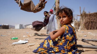 A girl sits as other children play on swings at a camp for internally displaced people in Marib, Yemen Feb. 16, 2021. (Reuters)