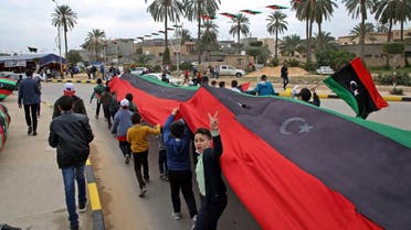 Libyan youth march with a giant national flag in the capital Tripoli on February 25, 2021, during celebrations commemorating the 10th anniversary of the 2011 revolution that toppled longtime dictator Muammar Gaddafi. (Mahmud Turkia/AFP)