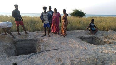 Local residents stand next to graves dug by the authorities to bury coronavirus victims after the government announced reversing its policy of forced cremations, at the islet of Iranaitivu off Sri Lanka's northern province, March 2, 2021. (AFP)