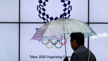 A man wearing a protective face mask walks past in front of a display showing the logo of Tokyo 2020 Olympic Games that have been postponed to 2021 due to the coronavirus disease (COVID-19) outbreak, in Tokyo, Japan, on January 23, 2021. (Reuters)
