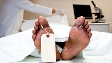 Mortician, coroner covering dead body in morgue. Feet, toe tag. stock photo