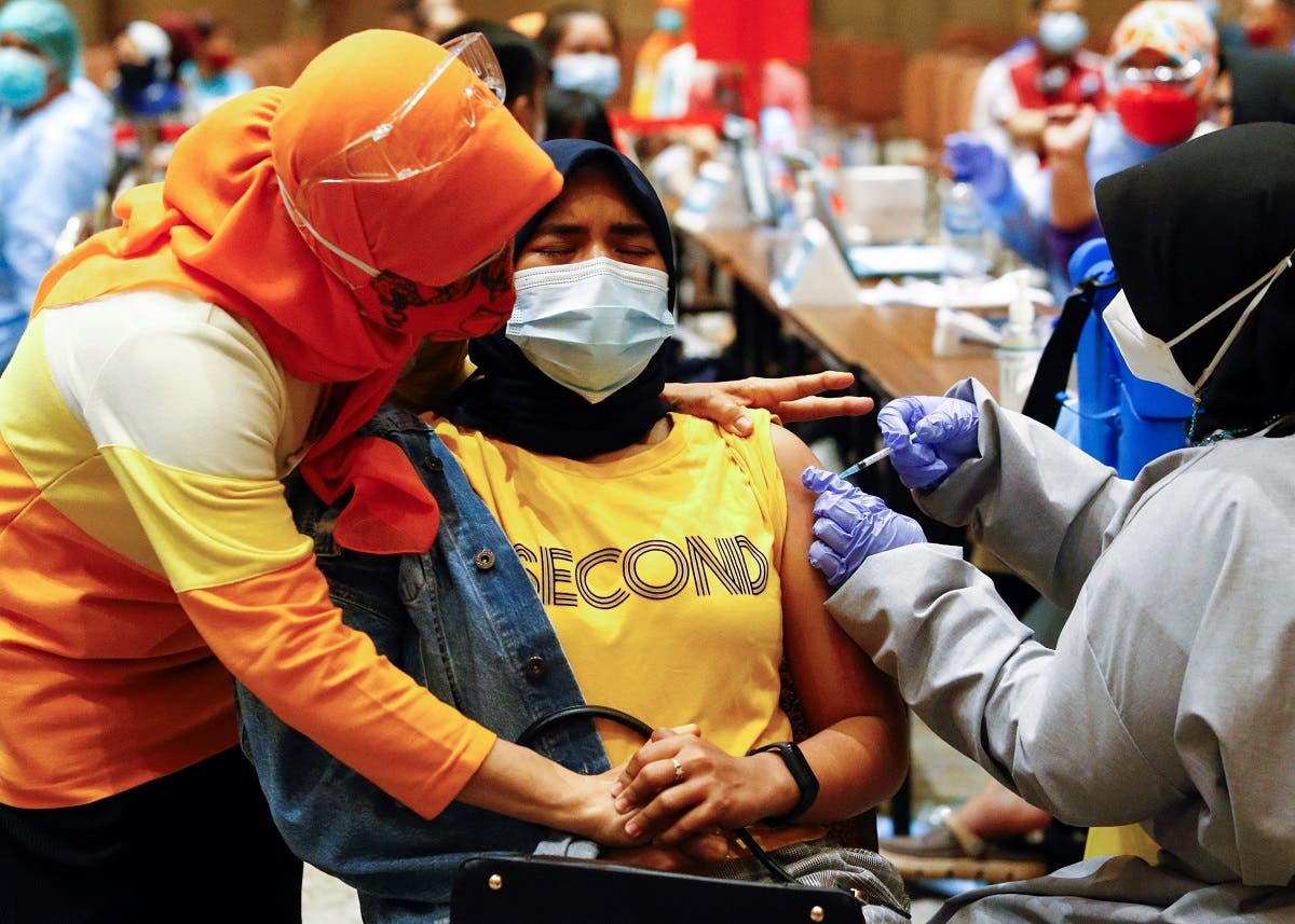 A woman reacts while receiving her first dose of China's Sinovac Biotech vaccine for the coronavirus disease (COVID-19) during a mass vaccination program for vendors and workers at a shopping mall in Tangerang, on the outskirts of Jakarta, Indonesia. (Reuters)