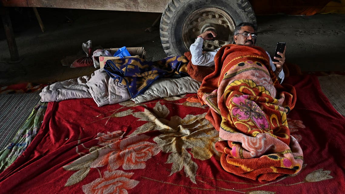 A Protesting farmer checks his mobile phone as he rests along a blocked highway as farmers continue the protest against the central government's recent agricultural reforms at Gazipur Delhi-Uttar Pradesh state border, in Ghaziabad on March 5, 2021. (AFP)