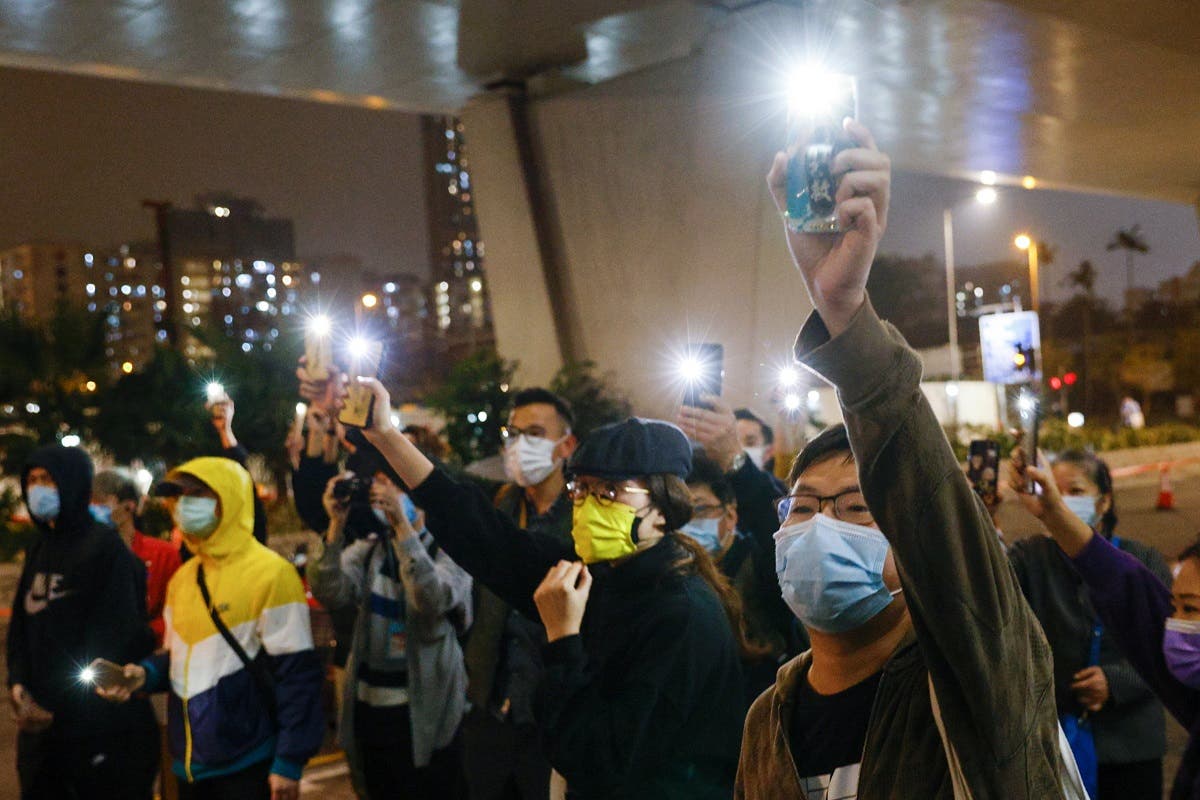 Supporters of 47 pro-democracy activists hold flashlights as they wait for four of them to leave the West Kowloon Magistrates’ Courts on bail, over a national security law charge, in Hong Kong, China, on March 5, 2021. (Reuters)