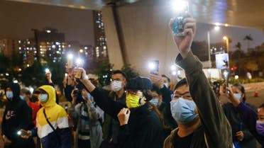 Supporters of 47 pro-democracy activists hold flashlights as they wait for four of them to leave the West Kowloon Magistrates’ Courts on bail, over a national security law charge, in Hong Kong, China, on March 5, 2021. (Reuters)