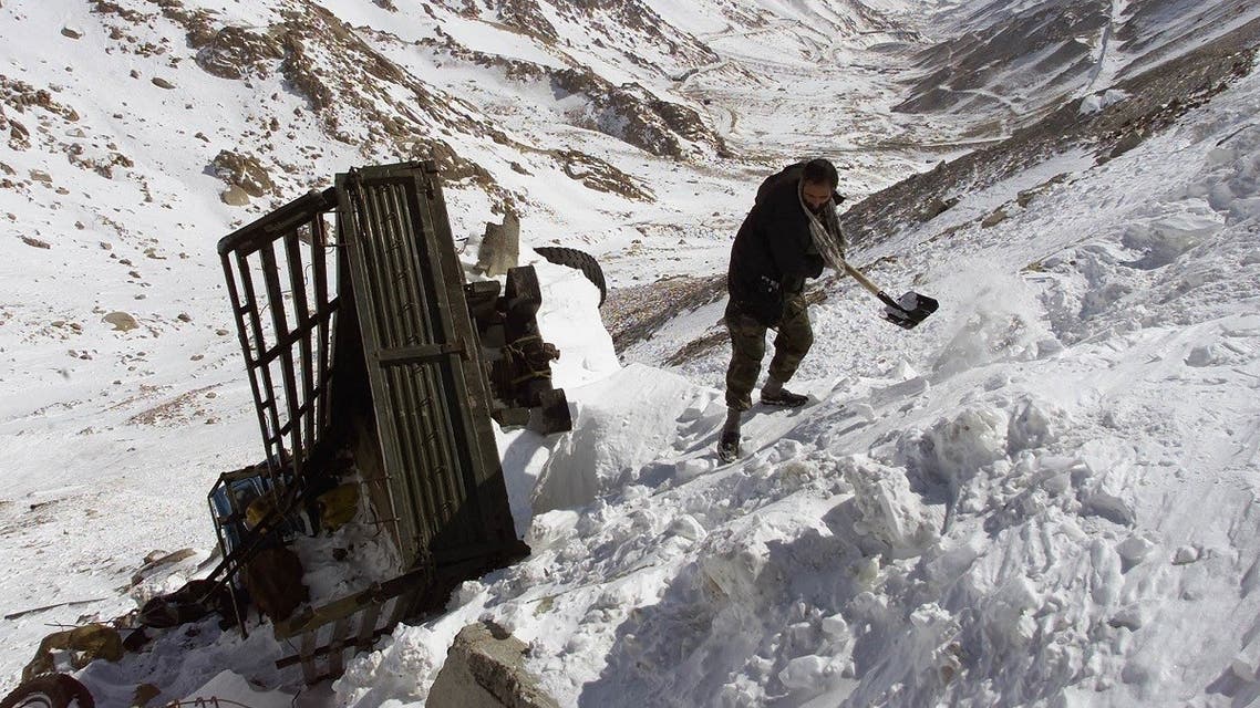 An Afghan driver clears snow from around his truck after it was swept off the road by an avalance on the south side of Salang tunnel, some 100 km north from Kabul. (File photo: Reuters)