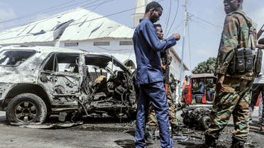 Officials gather beside debris at the site of a suicide car bombing attack near a security checkpoint in Mogadishu on February 13, 2021. (AFP)