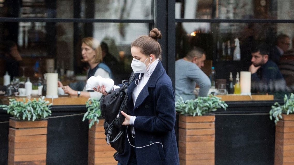 A woman, wearing a protective mask, walks past an opened restaurant in downtown Skopje on February 11, 2021. (AFP)