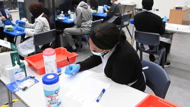 Health workers and volunteers handle lateral flow test samples and record results as students take coronavirus disease (COVID-19) tests at Harris Academy Beckenham, in Beckenham, south east London, Britain, March 5, 2021. (Reuters)