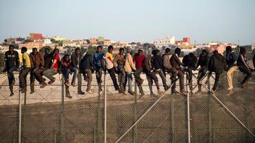 Would-be immigrants stand atop a boarder fence separating Morocco from the north African Spanish enclave of Melilla on October 22, 2014. (AFP)