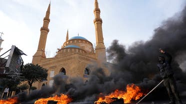 A demonstrator gestures near burning tires during a protest against the fall in Lebanese pound currency and mounting economic hardships, in Beirut, Lebanon March 8, 2021. (Reuters)
