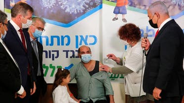 Israeli Prime Minister Benjamin Netanyahu (C) speaks during a visit at Clalit Health Service as an Israeli citizen receives a shot of the Covid-19 vaccine, in an Arab-Israeli village of Abu Ghosh near Jerusalem on March 9, 2021. (Gil Cohen-Magen/AFP)