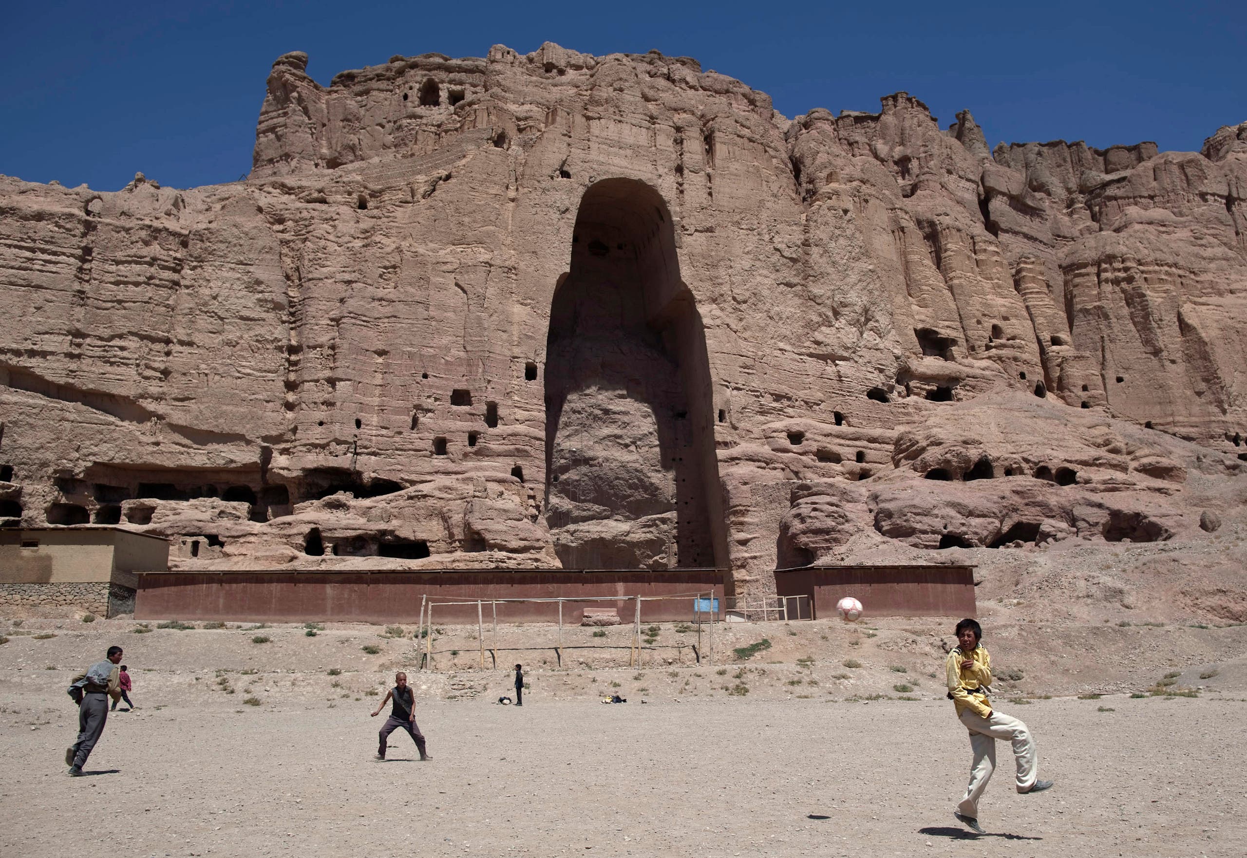 Afghan boys play soccer in front of the remains of a 1,500-year-old Buddha statue which was destroyed by the Taliban in March 2001, in the central province of Bamiyan August 22, 2011. (File photo: Reuters)