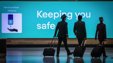 This picture taken on September 29, 2020 shows Qatar Airlines flight crew members walking past an illuminated sign displaying a message relating to the COVID-19 novel coronavirus at the Sydney International Airport in Sydney. (File photo: AFP)