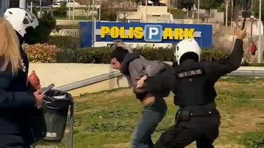 A police officer hits a man as he is being detained in Athens, Greece, March 7, 2021, in this screen grab taken from video. Handout via REUTERS ATTENTION EDITORS THIS IMAGE HAS BEEN SUPPLIED BY A THIRD PARTY.