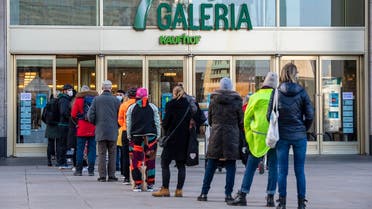 People queue up in front of a department store in Berlin’s Alexanderplatz shopping district on March 10, 2021, after some shops were allowed to open following a partial easing of lockdown restrictions, amid a coronavirus pandemic. (AFP)