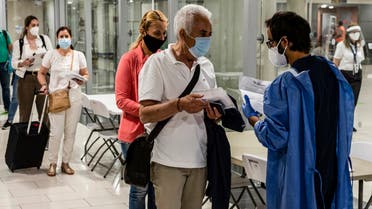 health worker checks the medical documents of mask-clad travellers arriving at Cyprus' Larnaca International Airport on June 9, 2020, before being screened for COVID-19 coronavirus symptoms on their way to passport control. (File photo: AFP)