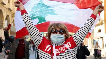 A demonstrator holds up a national flag during a protest in Beirut, Lebanon March 6, 2021. (Reuters)