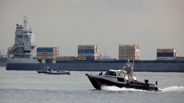 A police coast guard vessel patrols past container ship Valili carrying Islamic Republic of Iran Shipping Lines (IRISL) cargo in the waters of Singapore Strait off Sentosa island February 6, 2012. (Reuters)