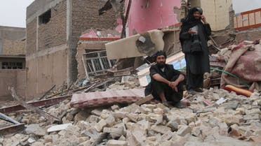 Residents stand amid the debris of a damaged house after a car bomb blast in Herat on March 13, 2021.