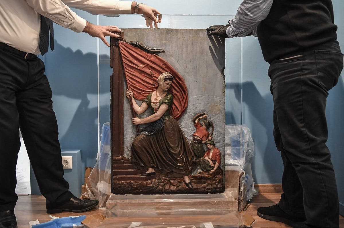 Museum employees unwrap an artwork depicting Greek revolution heroine, Laskarina Bouboulina in the new museum dedicated to the Philhellene foreign volunteers who fought and died for Greece on March 12, 2021. (Louisa Gouliamaki/AFP)