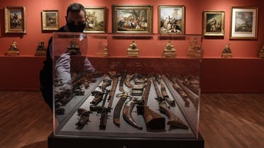 A museum employee closes a case displaying weapons in the new museum dedicated to the Philhellene foreign volunteers who fought and died for Greece on March 12, 2021. (Louisa Gouliamaki/AFP)