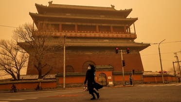 A woman walks past Drum Tower during morning rush hour as Beijing, China, is hit by a sandstorm, March 15, 2021. (Reuters)