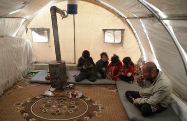 Mohammed Abu Rdan sits with his family inside a tent, at an internally displaced Syrian camp, in northern Aleppo, Syria March 11, 2021. (Reuters/Mahmoud Hassano)