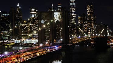 aces of victims of Covid-19 are projected onto the Brooklyn Bridge during a memorial service called “A COVID-19 Day of Remembrance” on March 14, 2021 in New York City. (File photo: AFP)